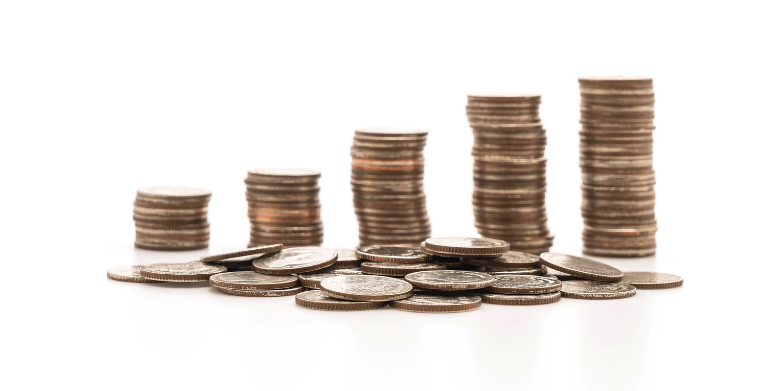 Montones de monedas cada vez más altos sobre fondo blanco