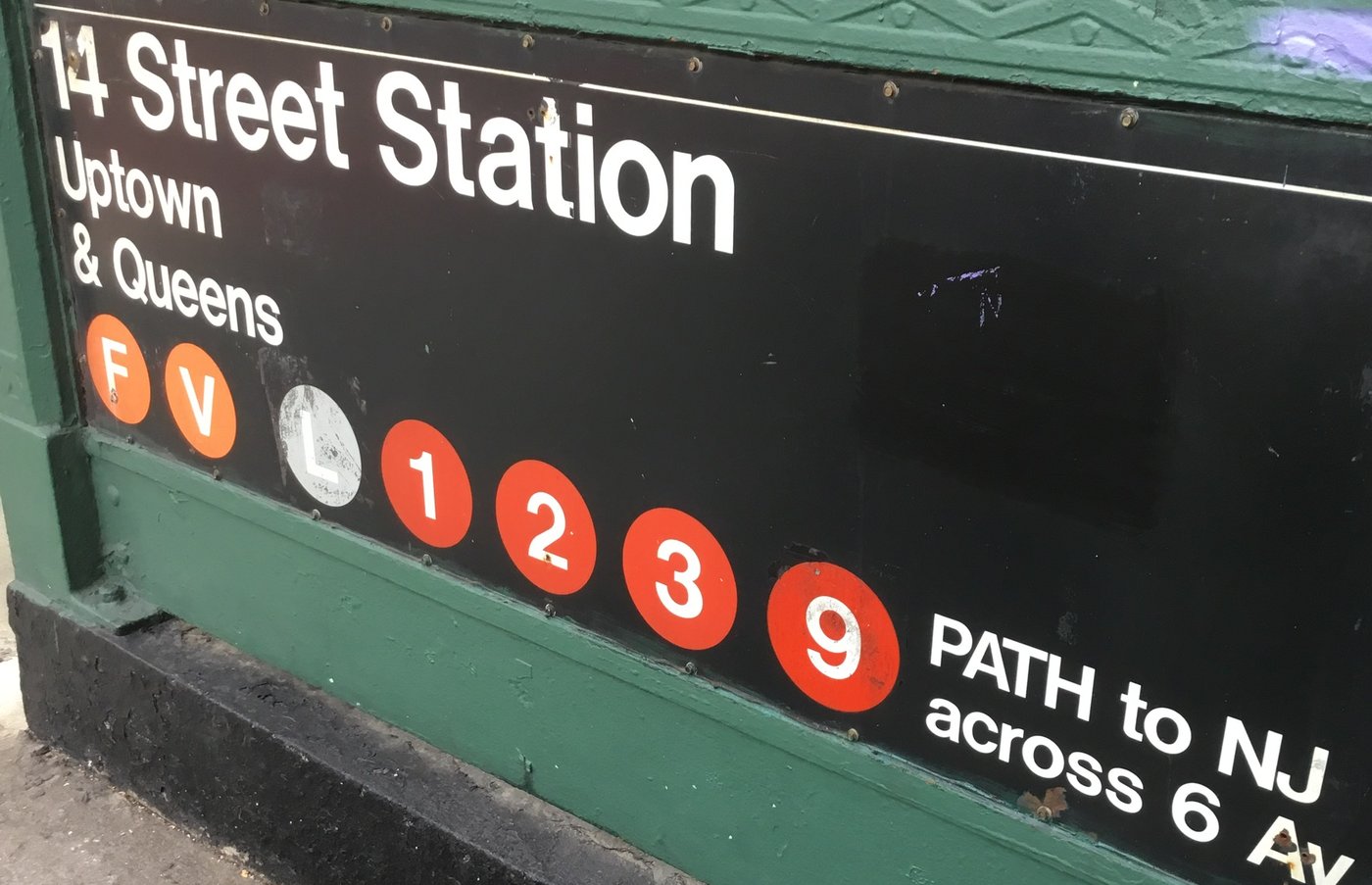 Cartell d'entrada de l'estació de metro 14th Street a Nova York, amb la tipografia Standard i els cercles de color de les línies F, V, L, 1, 2, 3 i 9